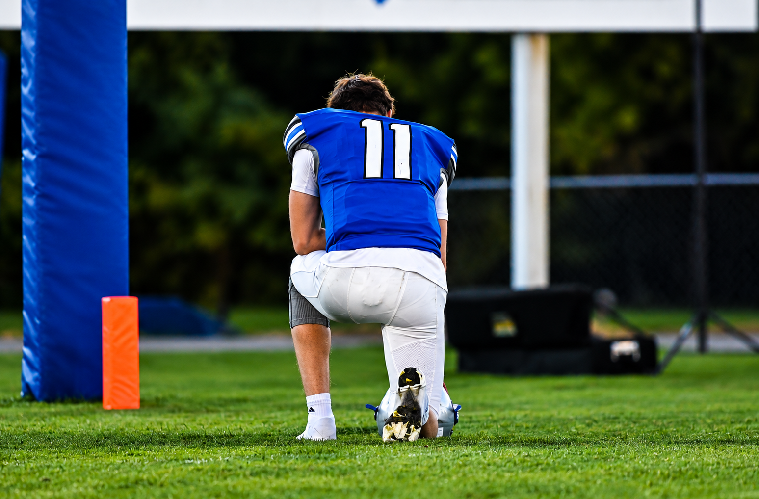 Player number 11 kneeling in prayer on the field